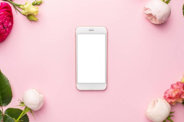 Cep telefonu ve pembe arkaplanlı Ranunculi çiçek buketi.