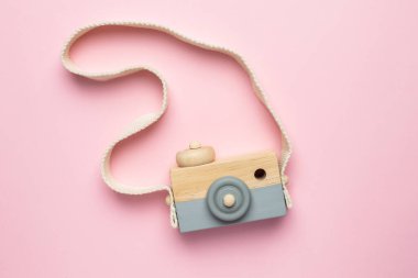 Pembe arka planda tahta bebek kamerası, doğal ekolojik malzemeler ve erken bebek gelişimi üst görünümü.