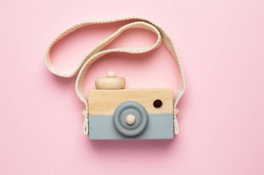 Pembe arka planda tahta bebek kamerası, doğal ekolojik malzemeler ve erken gelişim.