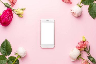 Cep telefonu ve pembe arkaplanlı Ranunculi çiçek buketi.