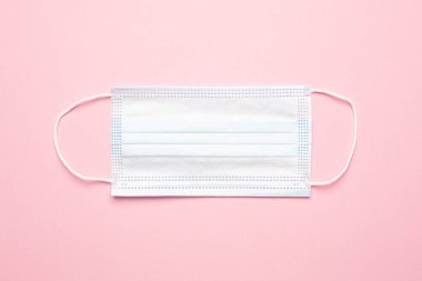 Pembe arka planda tıbbi maske, salgın ikinci dalga ve kovid enfeksiyondan korunma.