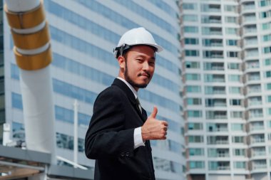 Buliding site üzerinden samrt mühendislik ayakta ve başparmak yukarıya, mutlu ekip çalışması kavramı gösterilen.