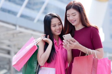 İki mutlu genç Asyalı kadın birlikte alışveriş.