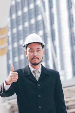 Buliding site üzerinden samrt mühendislik ayakta ve başparmak yukarıya, mutlu ekip çalışması kavramı gösterilen.