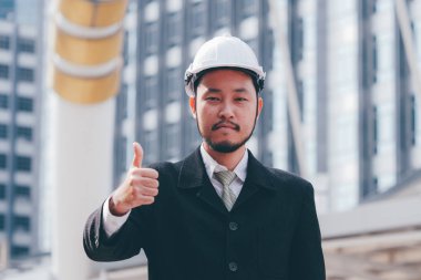 Buliding site üzerinden samrt mühendislik ayakta ve başparmak yukarıya, mutlu ekip çalışması kavramı gösterilen.