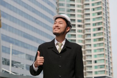 Buliding site üzerinden samrt mühendislik ayakta ve başparmak yukarıya, mutlu ekip çalışması kavramı gösterilen.