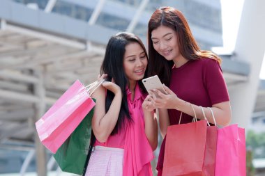 İki mutlu genç Asyalı kadın birlikte alışveriş.