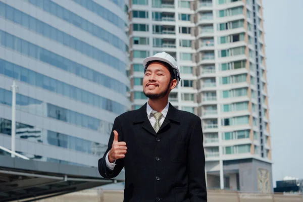 Buliding site üzerinden samrt mühendislik ayakta ve başparmak yukarıya, mutlu ekip çalışması kavramı gösterilen.