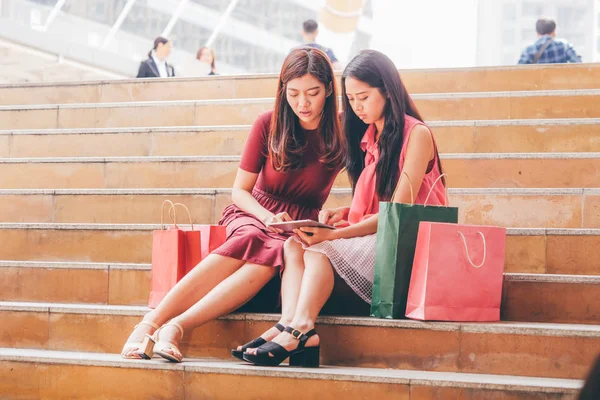 İki mutlu genç Asyalı kadın birlikte alışveriş.