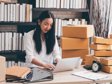 Pacel kutuları arka plan ile dizüstü bilgisayar kullanarak çalışan Asain kadın.