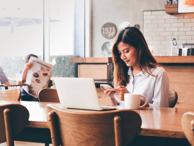 Kafede dizüstü bilgisayar ile çalışan Asain kadın.