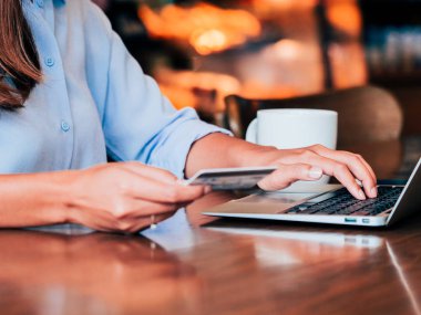 Kredi kartı ve kafede dizüstü ile asain kadın eller yukarı kapatın.