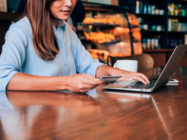 Kredi kartı ve kafede dizüstü ile asain kadın eller yukarı kapatın.