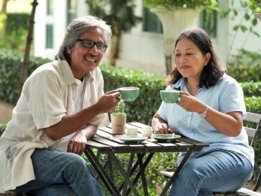 Ev bahçesinde kahve içerken kıdemli çift gülüyor..