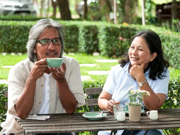 自宅の庭でコーヒーを飲みながら笑う先輩夫婦 — ストック写真