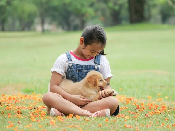 公園でかわいいゴールデンレトリーバー犬と遊ぶ小さなアジアの女の子 — ストック写真