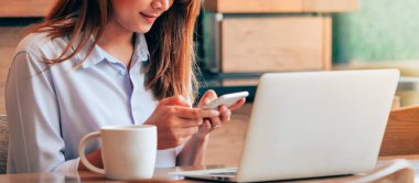 Kahve dükkanında akıllı telefon kullanan Asain kadın Branner.