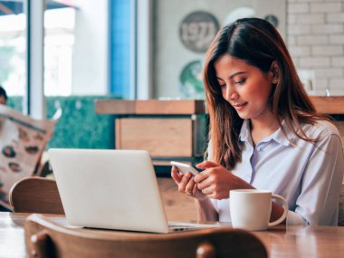 Kafede dizüstü bilgisayar ile çalışan Asain kadın.