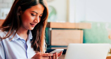 Kahve dükkanında akıllı telefon kullanan Asain kadın Branner.