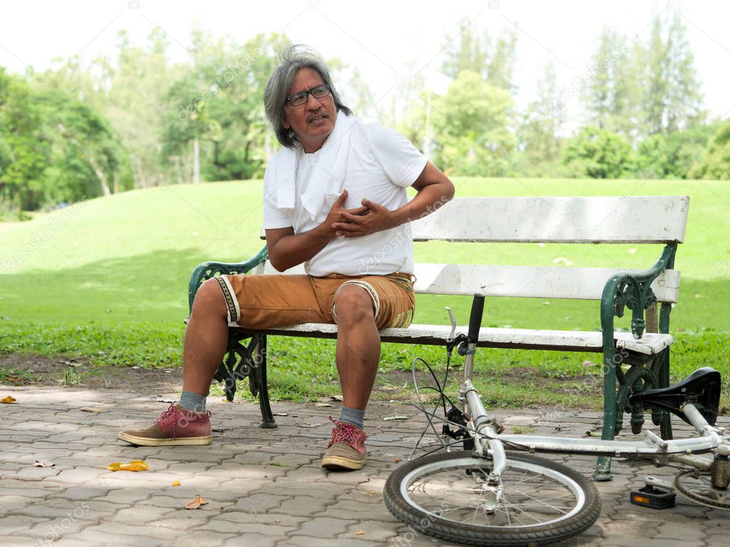 Senior man hurt heart,he take a rest in the park after cycling.