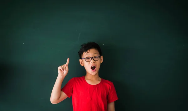 Asian boy with book on blackboard background education school cl — Stock Photo, Image