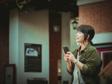 Asyalı kadın alışveriş merkezi mutlu ruh hali ile Smartphone kullanarak