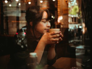 Asyalı kadın kahve dükkanı kafede kahve içme  