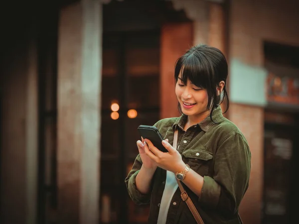 Mulher asiática usando smartphone com humor feliz no shopping — Fotografia de Stock