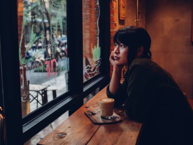 Asyalı kadın kahve dükkanı kafede kahve içme  