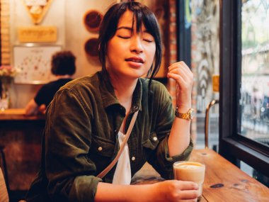 Asyalı kadın kahve dükkanı kafede kahve içme  