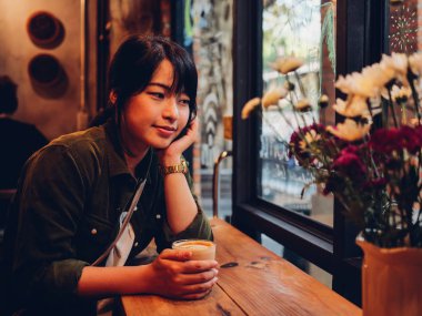 Asyalı kadın kahve dükkanı kafede kahve içme  