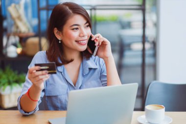 Asyalı kadın kredi kartı ve dizüstü compu ile cep telefonu kullanarak