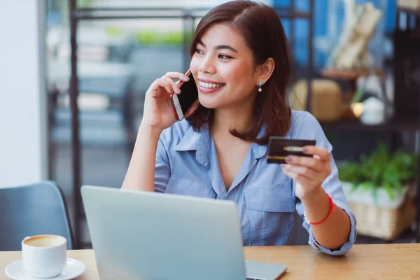 Asiatisk kvinne som bruker mobiltelefon med kredittkort og bærbar datamaskin – stockfoto