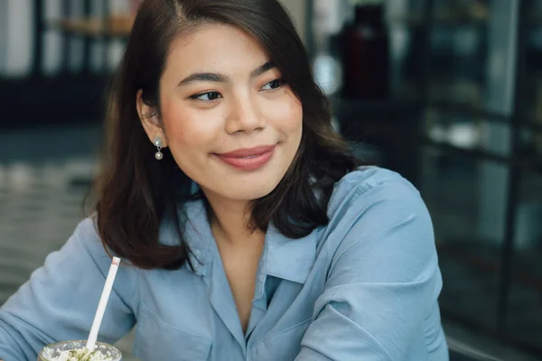 Kafede mavi gömlekli Asyalı kadın kahve içiyor ve konuşuyor w — Stok fotoğraf
