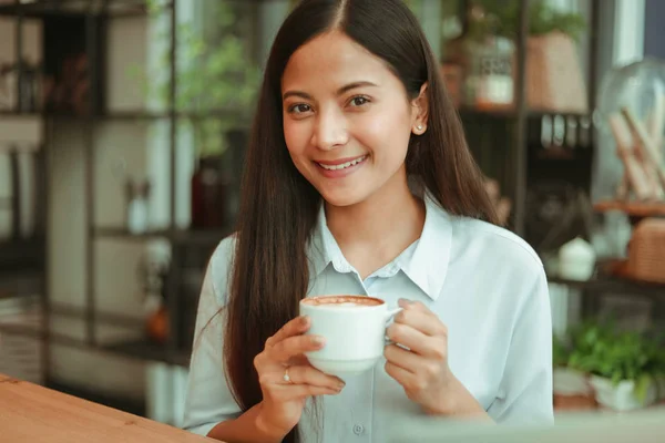 Asiatisk kvinna i blå skjorta arbeta och dricka kaffe i Coffee SHO — Stockfoto