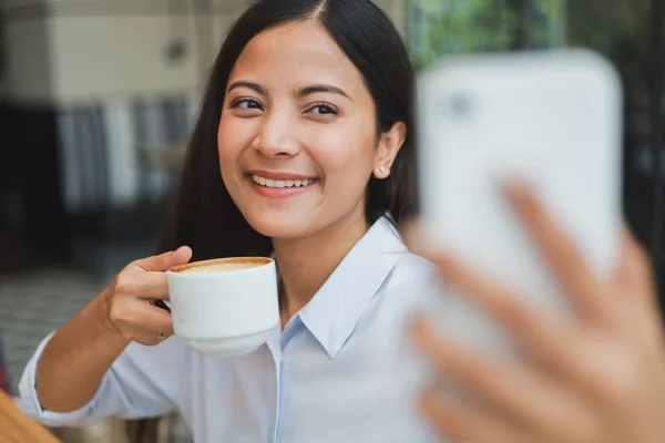 Asiática mujer selfie con teléfono móvil en café café sonrisa a — Foto de Stock