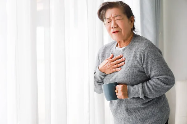 Asiatische Seniorin krankt mit Herzattacke im Wohnzimmer — Stockfoto