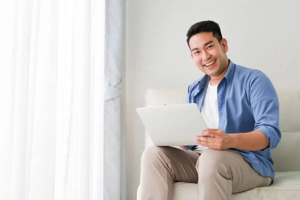 Asian handsome man working with laptop computer   in living room — Stock Photo, Image