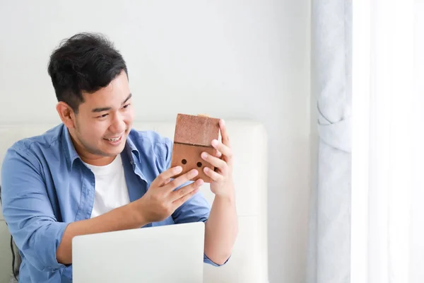 Junger asiatischer Mann in blauem Hemd mit Laptop und kleinem Computer — Stockfoto