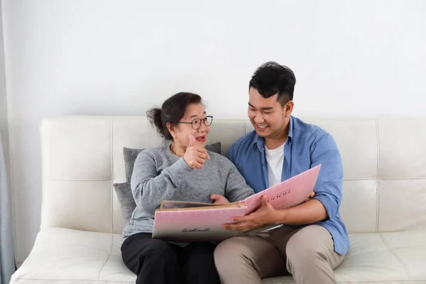 Asiatische Seniorin Mutter und junger Mann Sohn in blauem Hemd lookin — Stockfoto