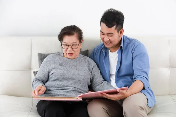 Asiatische Seniorin Mutter und junger Mann Sohn in blauem Hemd lookin — Stockfoto