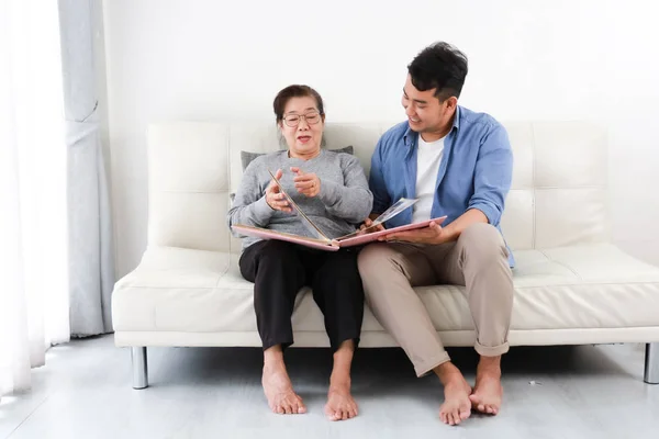 Asiatische Seniorin Mutter und junger Mann Sohn in blauem Hemd lookin — Stockfoto