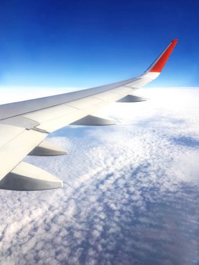 Uçuş sırasında bulutların arka planındaki uçağın kanadı.