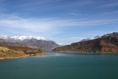 Özbekistan 'ın Taşkent ilinin arka planında dağlar bulunan Charvak Gölü rezervuarına bak