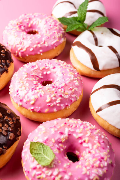Colorful donuts on rose background