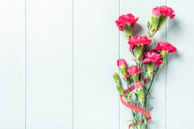 Açık turkuaz ahşap arka planda pembe karanfil buketi