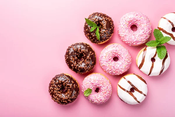 Donat warna-warni pada latar belakang mawar — Stok Foto