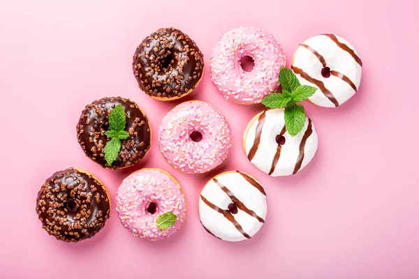 Donat warna-warni pada latar belakang mawar — Stok Foto