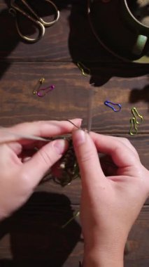 Dümdüz uzanmış, kadın elleri yeşil çorap örüyor. Ahşap masa ve bir fincan kahveyle rahat bir atmosfer. Tam HD görüntüler dikey video. Sert ışık