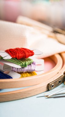 Canlı nakış iplikleri ahşap bir çemberde düzgün bir şekilde düzenlenir, dikiş iğneleri ve yumuşak kumaşla birlikte, rahat bir zanaat atmosferi yaratılır, fotokopi alanı ile telefon arka planı oluşturulur